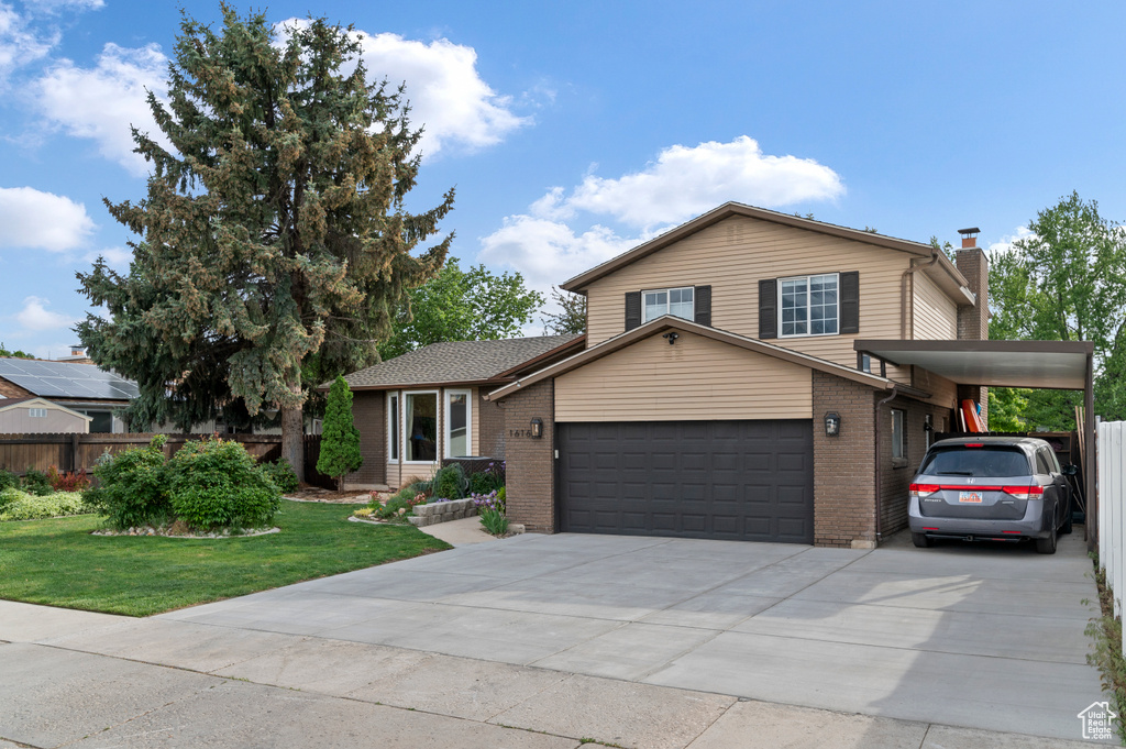 Tri-level home with brick siding, an attached garage, a chimney, and concrete driveway