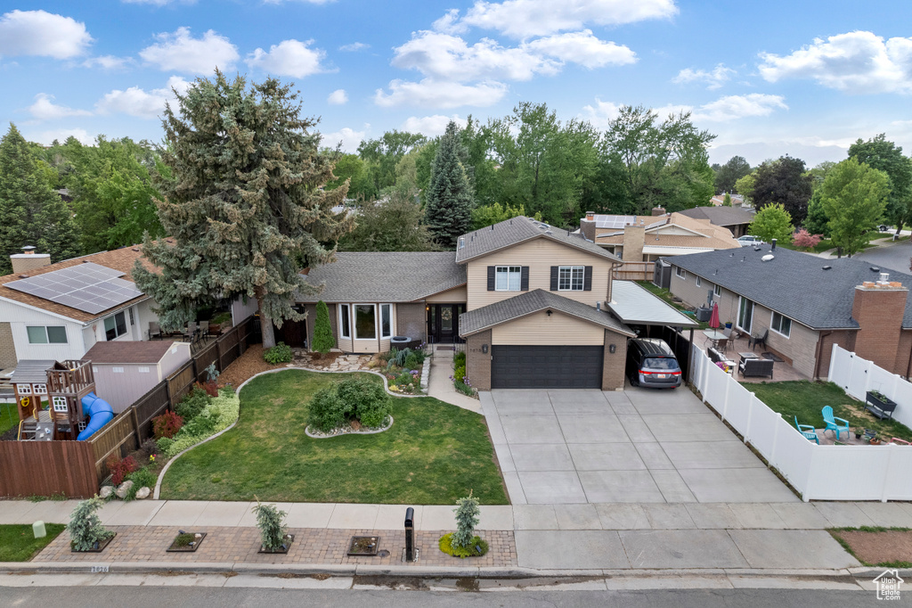 View of front of property with a carport, brick siding, a residential view, a garage, and driveway