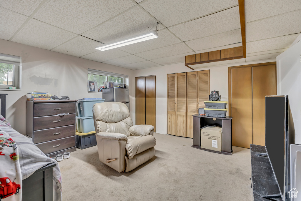 Bedroom with a drop ceiling, light carpet, two closets, and multiple windows