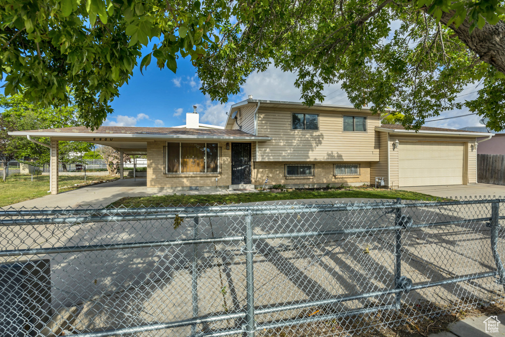 View of front of home featuring concrete driveway, a carport, a chimney, and brick siding
