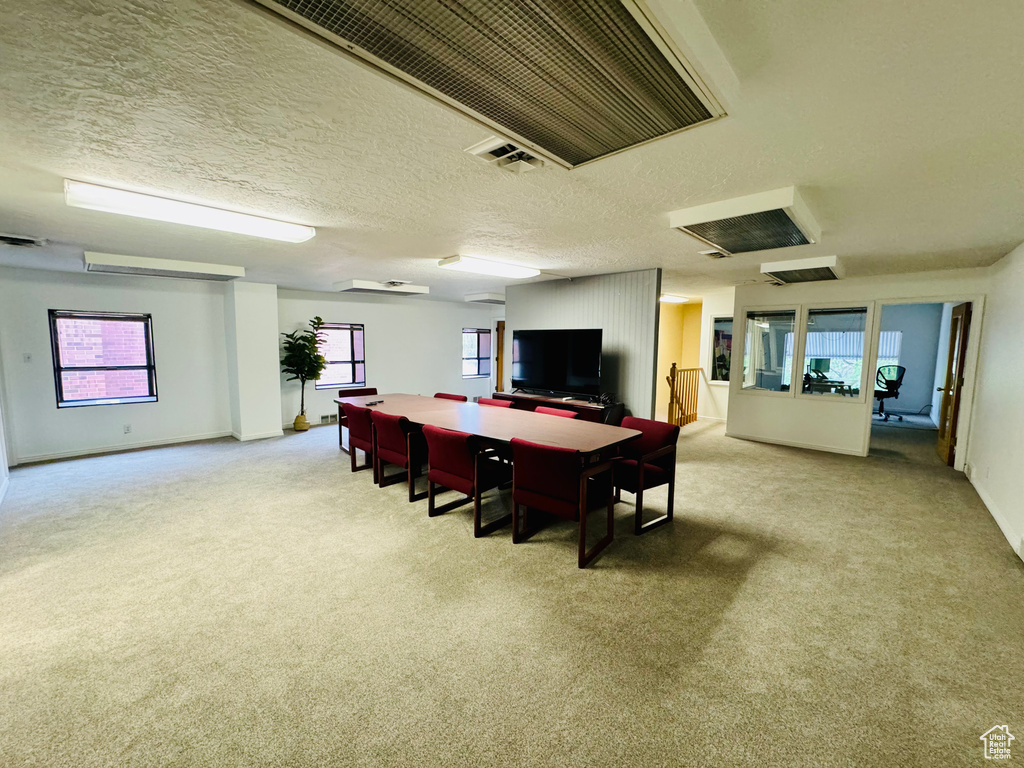Dining space featuring light carpet and a textured ceiling