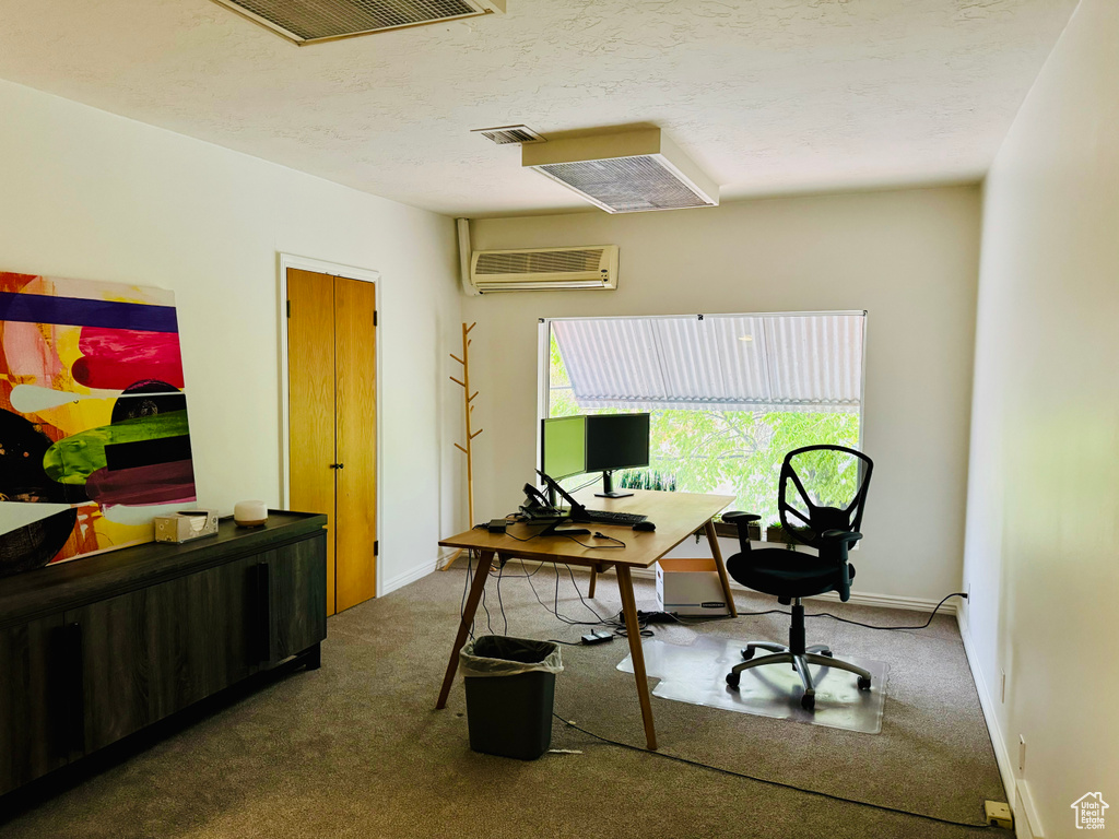 Carpeted office space with a wall unit AC and baseboards