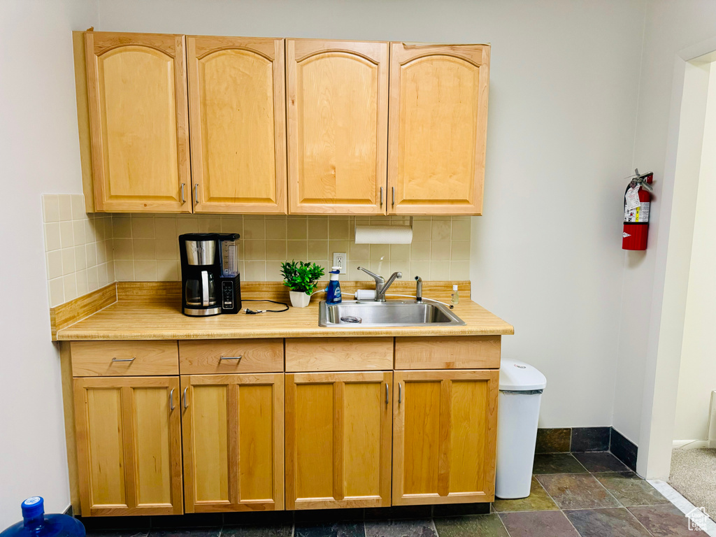 Kitchen featuring a sink, tasteful backsplash, light countertops, light brown cabinets, and baseboards