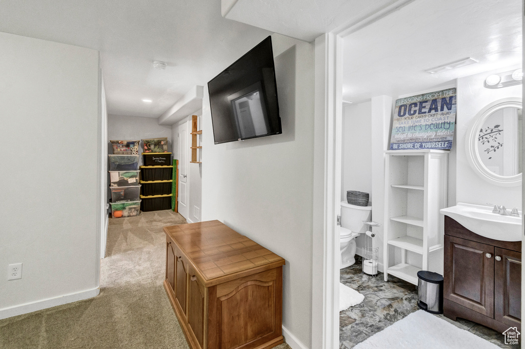 Hall featuring a sink, baseboards, and light carpet