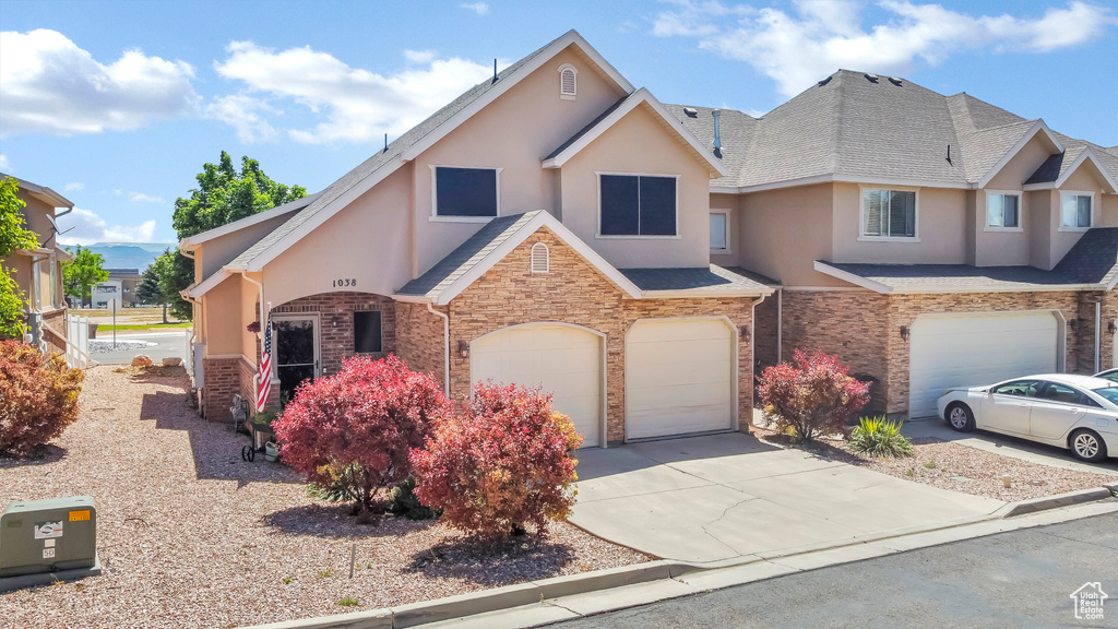 View of front of house featuring stucco siding, a garage, driveway, and stone siding