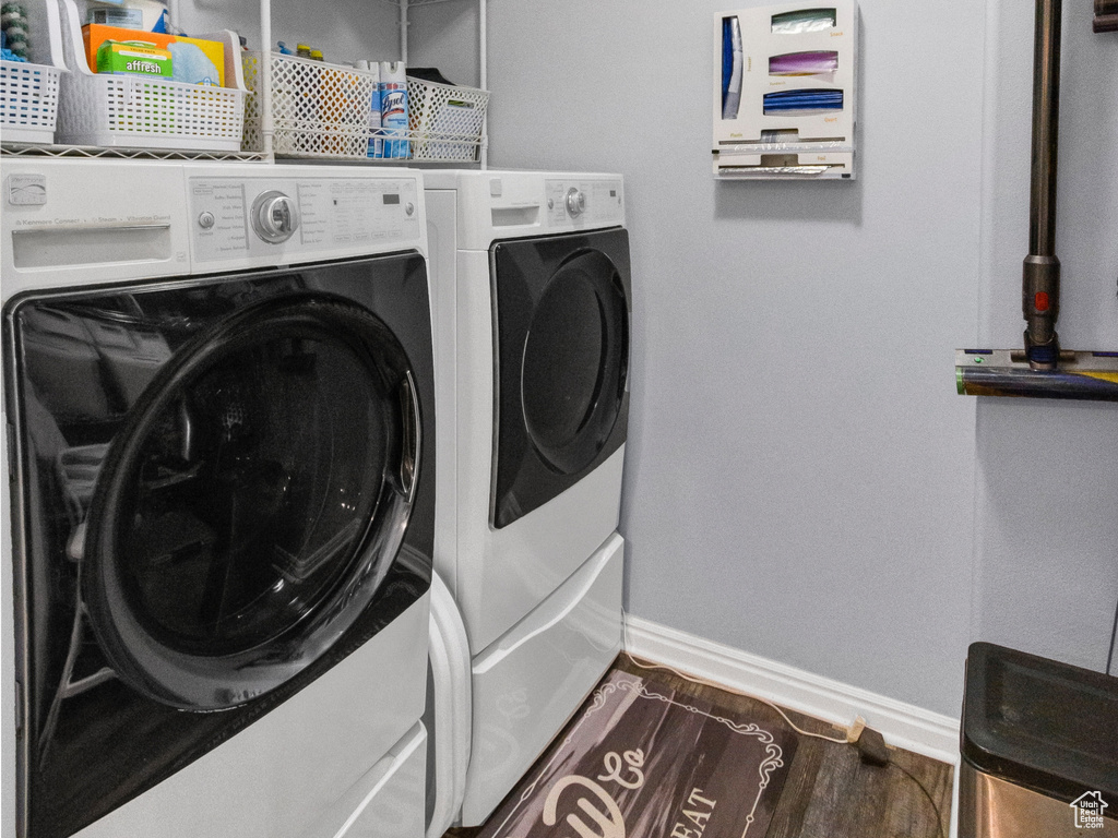 Laundry area with washing machine and dryer, wood finished floors, and baseboards