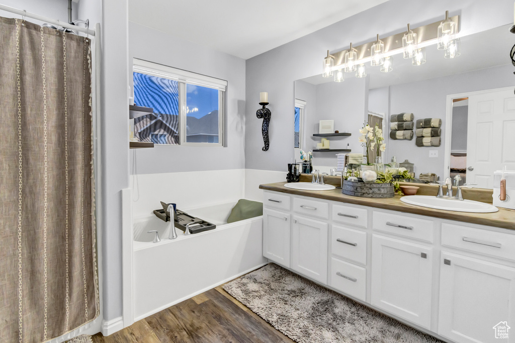 Full bath featuring double vanity, a garden tub, wood finished floors, and a shower with curtain