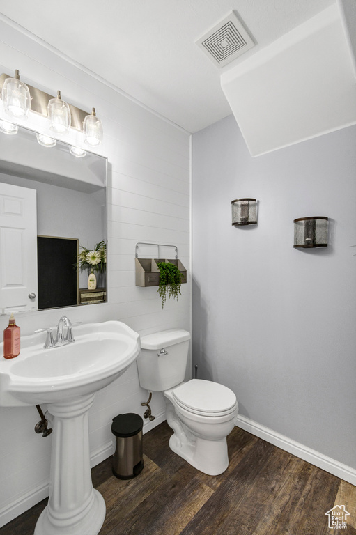 Bathroom featuring wood finished floors, toilet, and baseboards