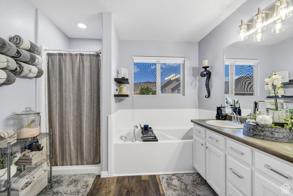 Full bath with vanity, a bath, wood finished floors, a shower with curtain, and recessed lighting