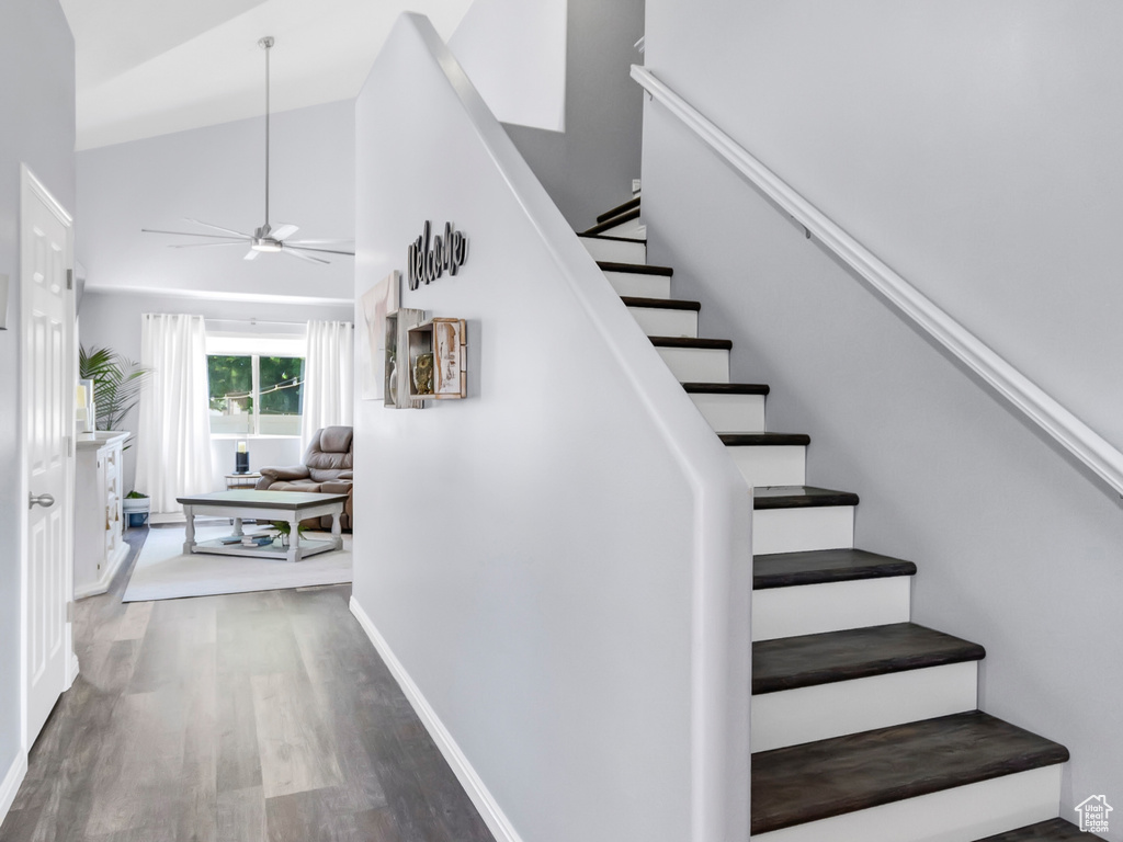 Staircase with wood finished floors, ceiling fan, high vaulted ceiling, baseboards, and recessed lighting