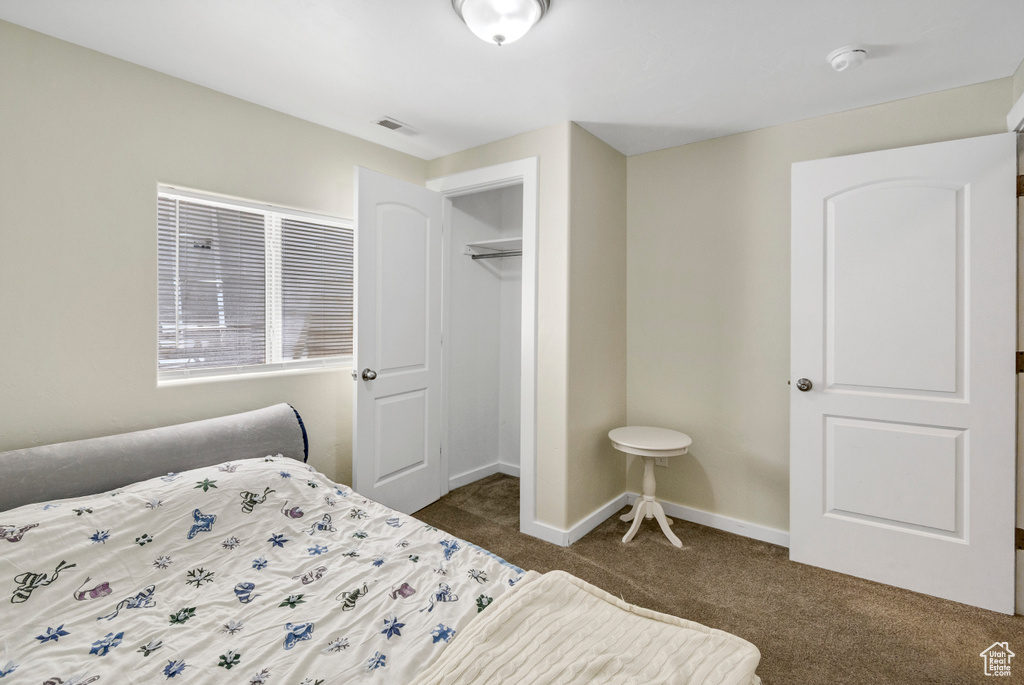 Bedroom with dark colored carpet, baseboards, and a closet