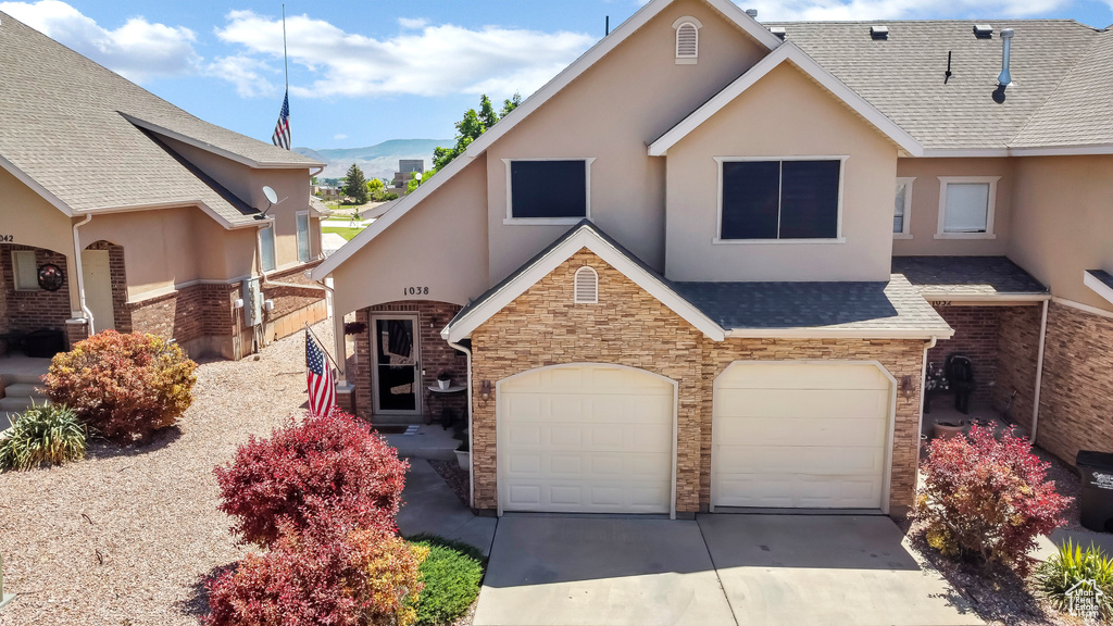 View of front of property featuring stucco siding, concrete driveway, a garage, stone siding, and a shingled roof