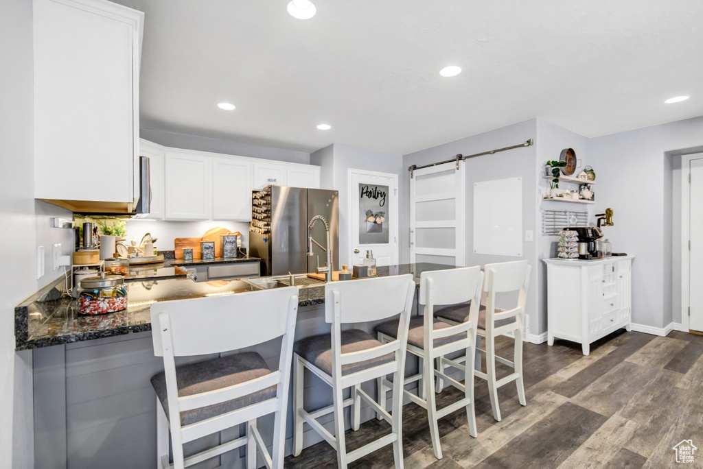 Kitchen featuring a barn door, freestanding refrigerator, recessed lighting, white cabinetry, and a peninsula