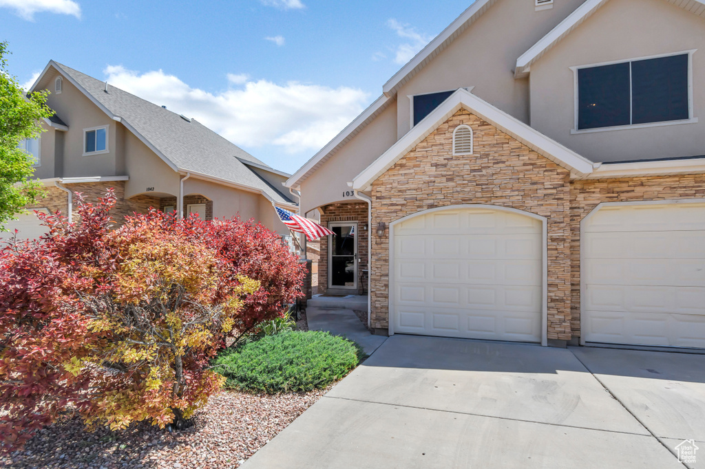 View of front facade featuring stone siding, stucco siding, and driveway