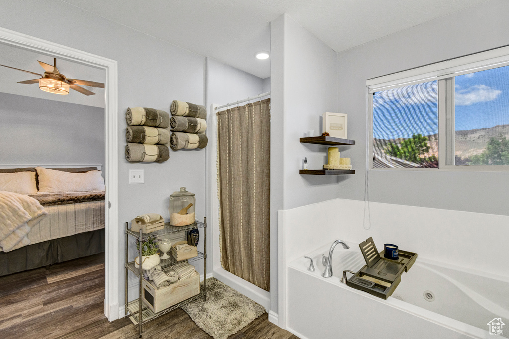 Bathroom with connected bathroom, wood finished floors, a jetted tub, a ceiling fan, and curtained shower