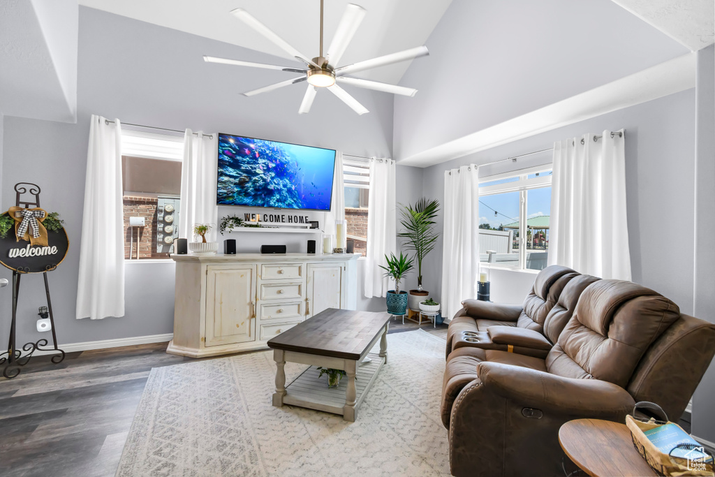 Living area featuring a ceiling fan, wood finished floors, baseboards, and high vaulted ceiling