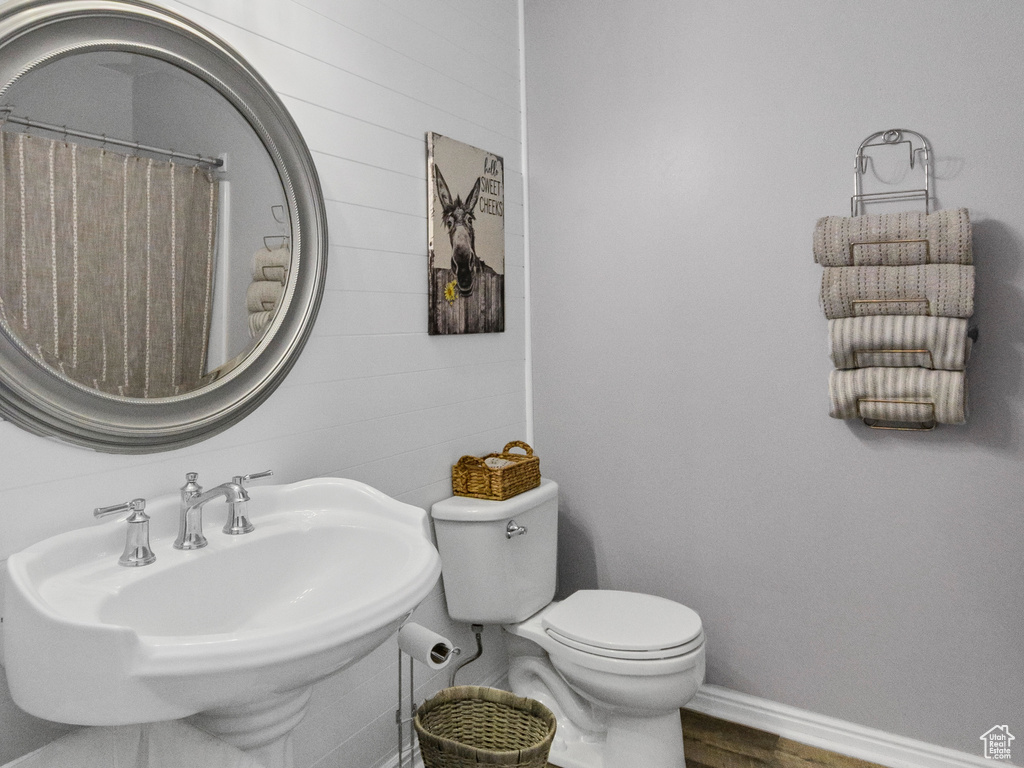 Bathroom featuring toilet, wood finished floors, baseboards, a textured ceiling, and a sink