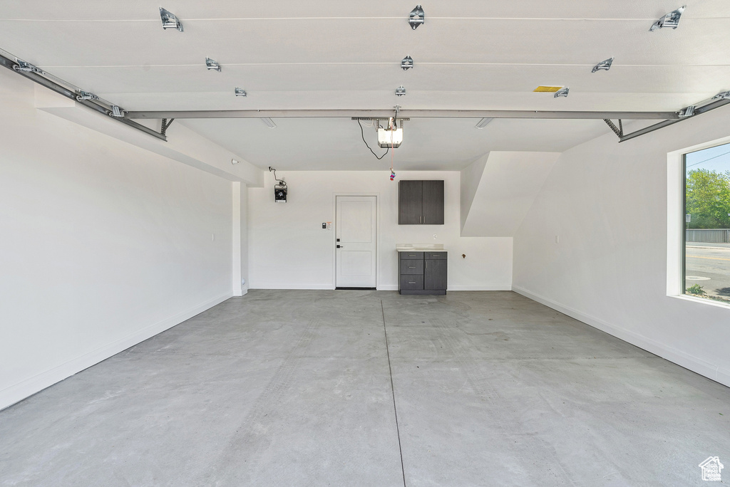 Garage featuring a garage door opener and baseboards