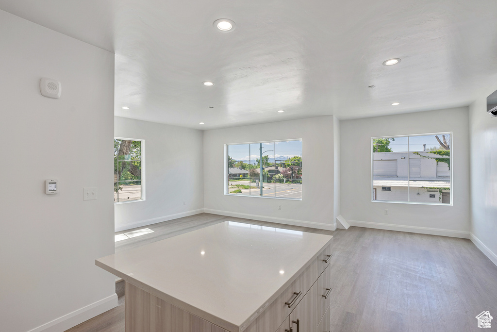 Kitchen with recessed lighting, light wood finished floors, baseboards, open floor plan, and light countertops