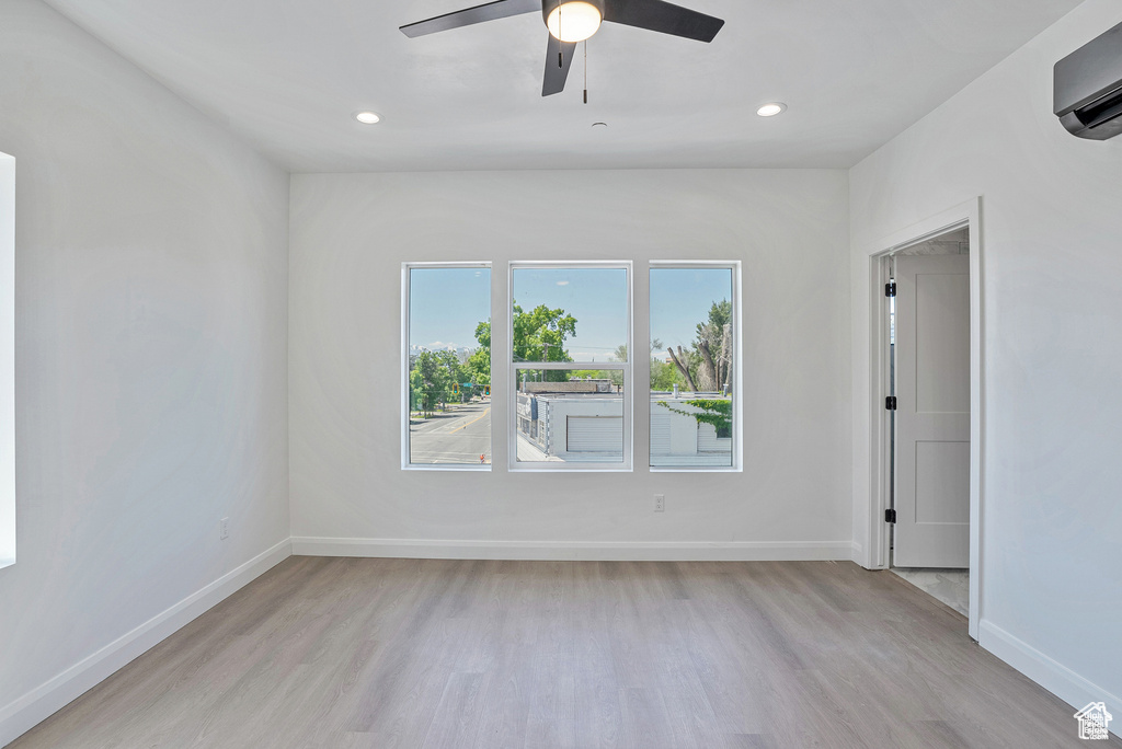 Spare room with light wood-style floors, a wall unit AC, baseboards, recessed lighting, and a ceiling fan