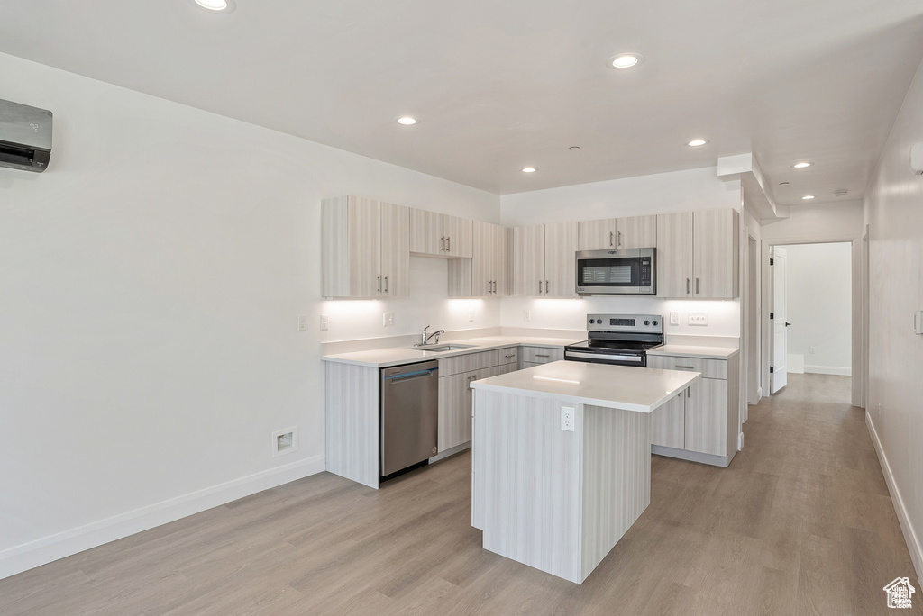 Kitchen with stainless steel appliances, a sink, a kitchen island, light wood-style flooring, and recessed lighting