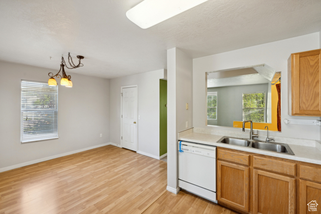 Kitchen featuring dishwasher, a sink, light wood-style flooring, and plenty of natural light