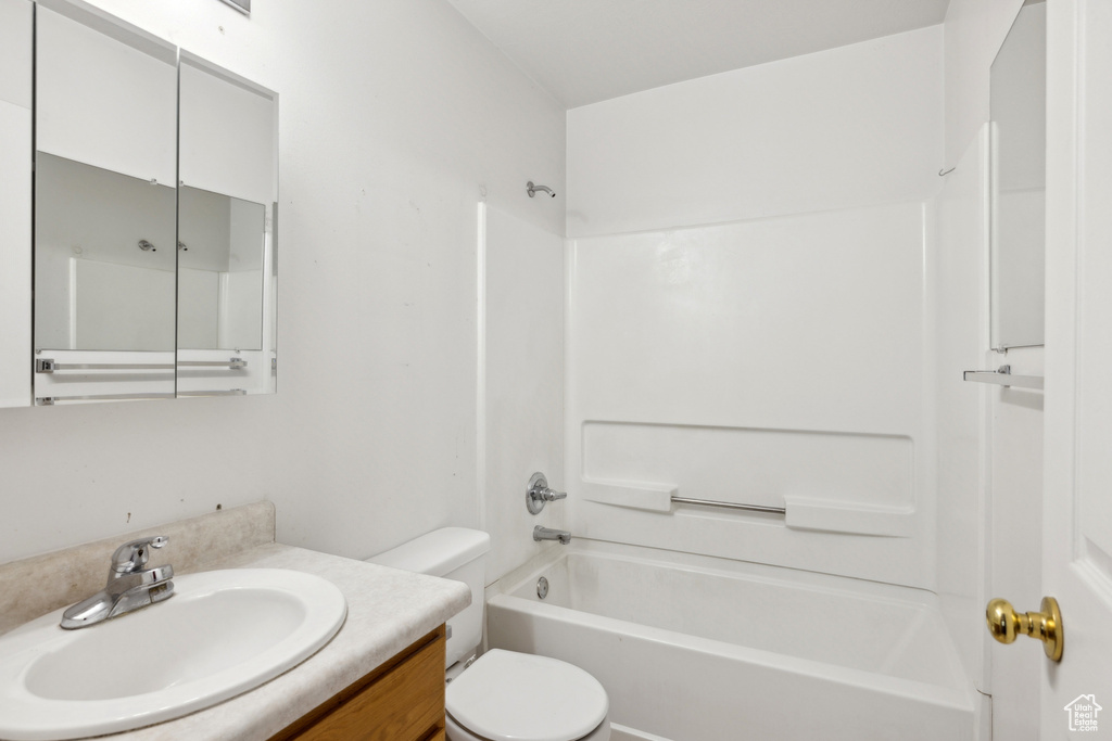 Bathroom featuring toilet, shower / bathtub combination, and vanity