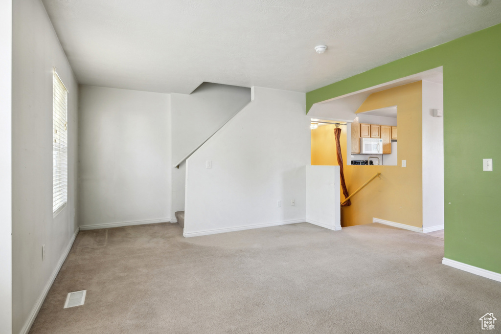 Unfurnished living room featuring carpet and baseboards