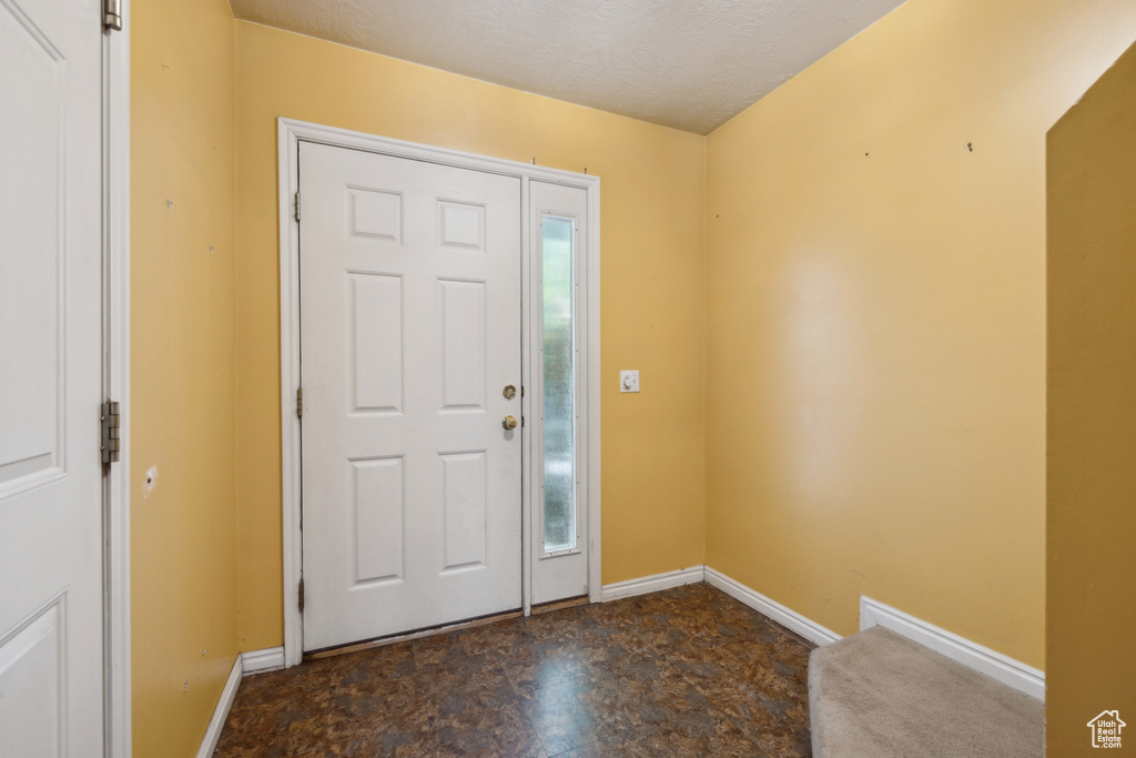 Foyer entrance with baseboards and a textured ceiling