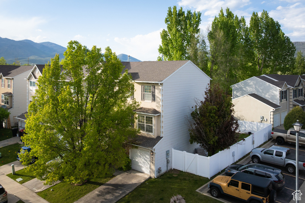 View of front of property featuring an attached garage, a residential view, a mountain view, and driveway