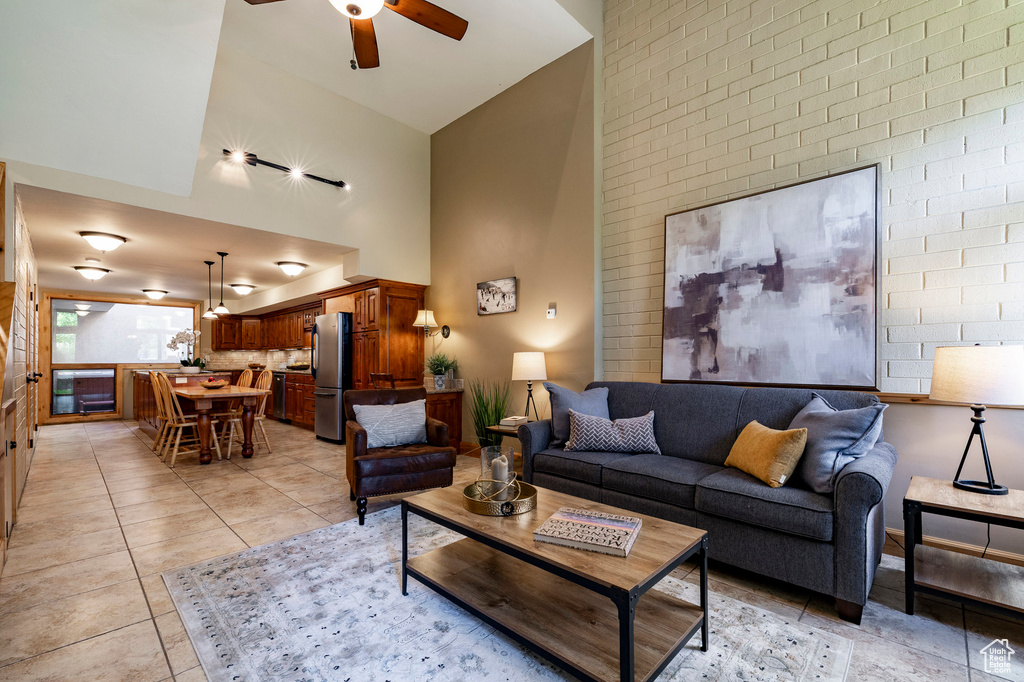 Living room with high vaulted ceiling, a ceiling fan, and light tile patterned floors