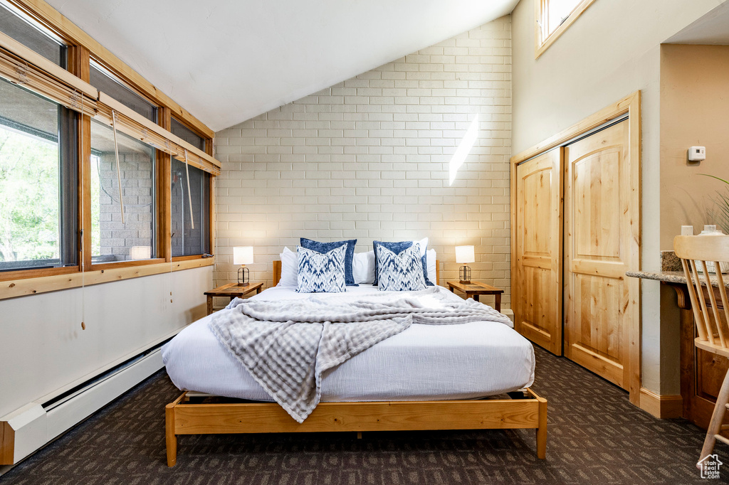 Carpeted bedroom featuring baseboard heating, vaulted ceiling, and multiple windows