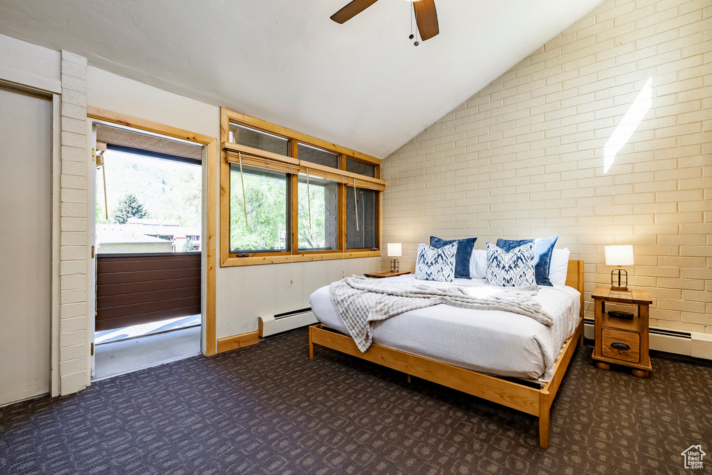 Carpeted bedroom with a baseboard radiator, lofted ceiling, brick wall, and a ceiling fan