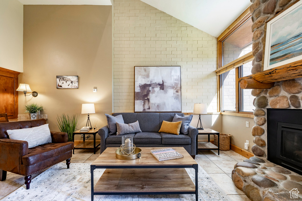 Living area featuring lofted ceiling, a fireplace, and light tile patterned floors