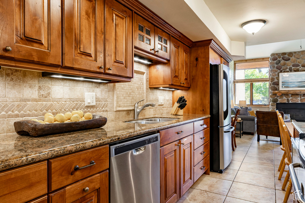 Kitchen with stainless steel appliances, a sink, stone counters, and tasteful backsplash