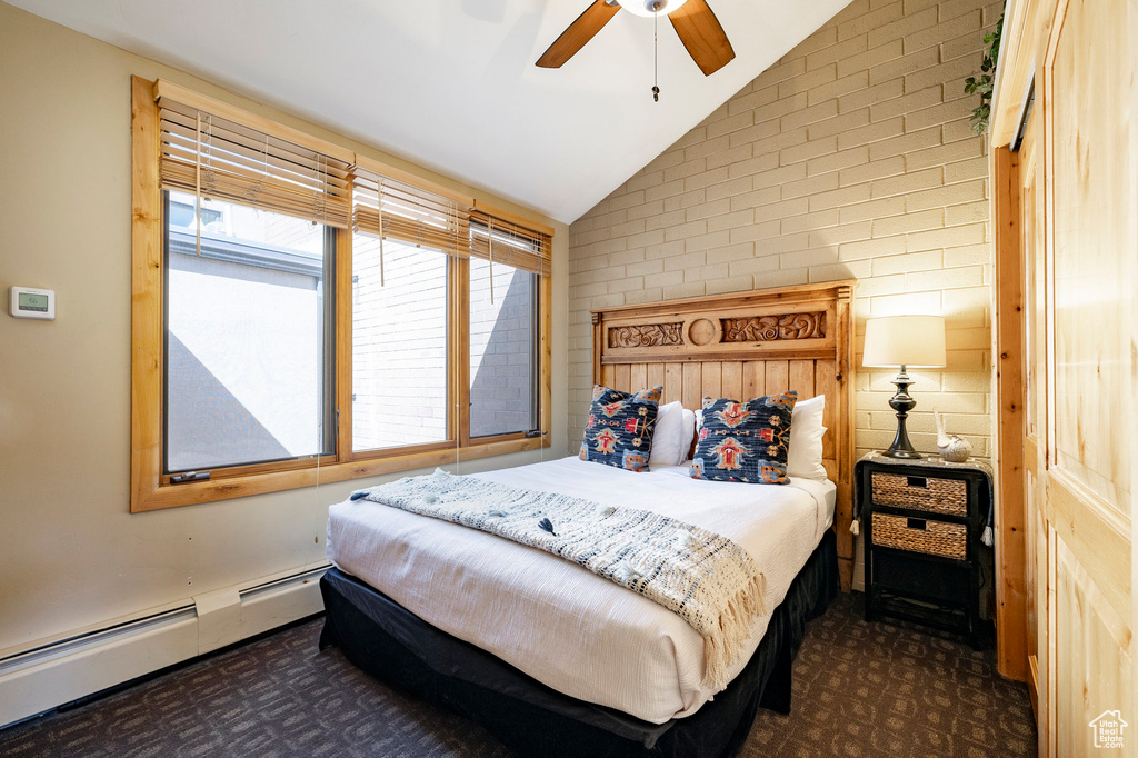 Bedroom featuring lofted ceiling, a baseboard heating unit, dark carpet, and a ceiling fan