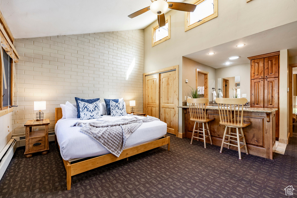 Bedroom with dark colored carpet, high vaulted ceiling, and a baseboard heating unit