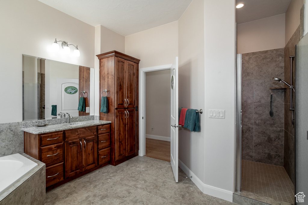 Bathroom with vanity, a tile shower, a garden tub, and baseboards