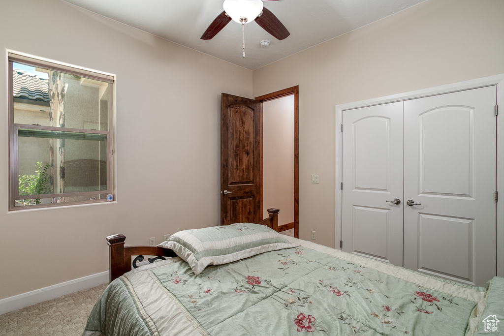 Carpeted bedroom with a closet, baseboards, and a ceiling fan
