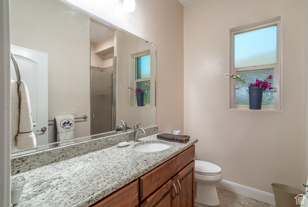 Full bath featuring a shower stall, vanity, toilet, baseboards, and tile patterned floors