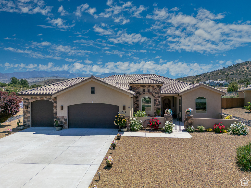 Mediterranean / spanish-style home featuring stucco siding, a garage, a mountain view, and driveway