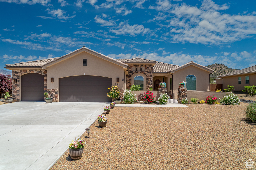 Mediterranean / spanish-style house featuring a garage, stucco siding, a tile roof, and driveway