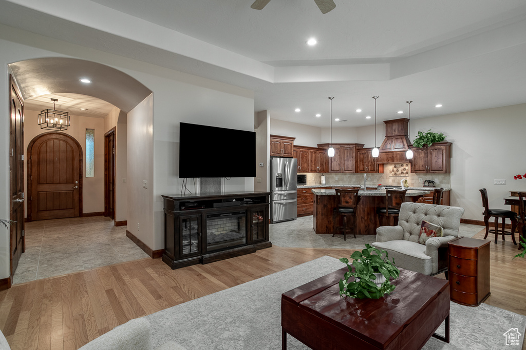 Living room with arched walkways, light wood-style flooring, recessed lighting, baseboards, and ceiling fan
