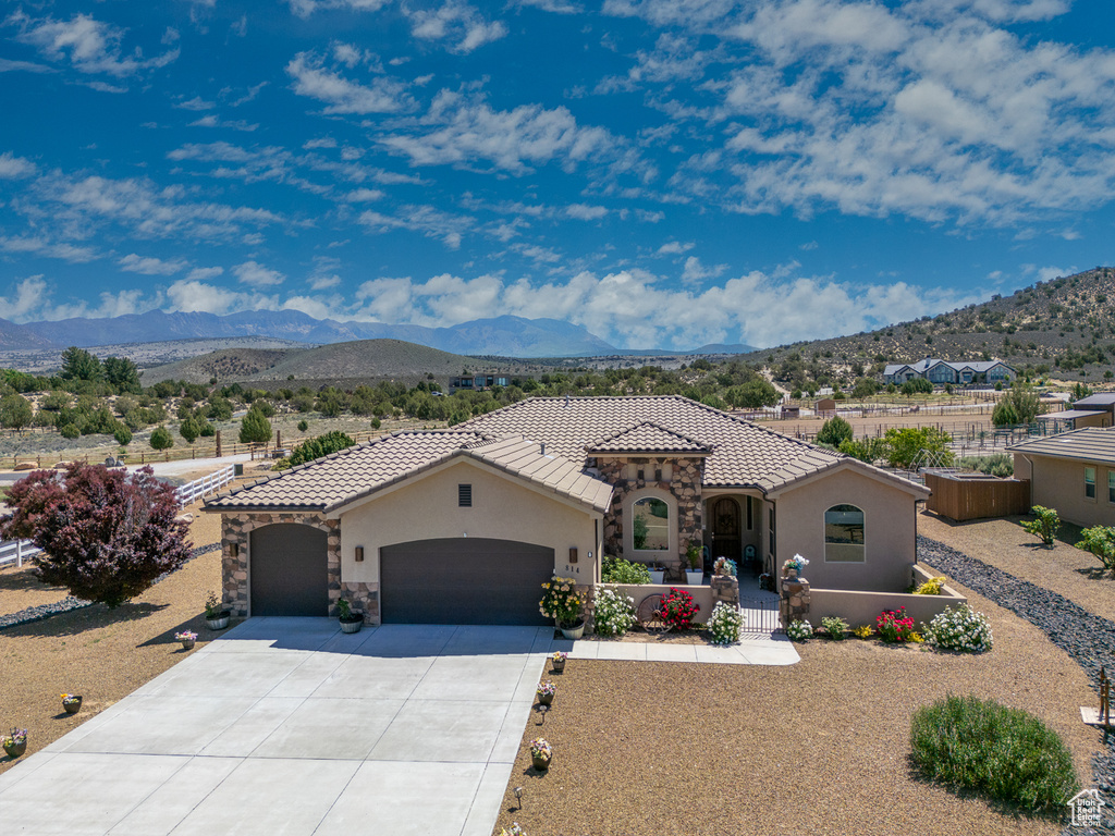 Mediterranean / spanish-style home with an attached garage, stucco siding, and a mountain view