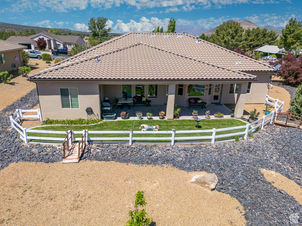 Back of property featuring a tiled roof, stucco siding, and a patio