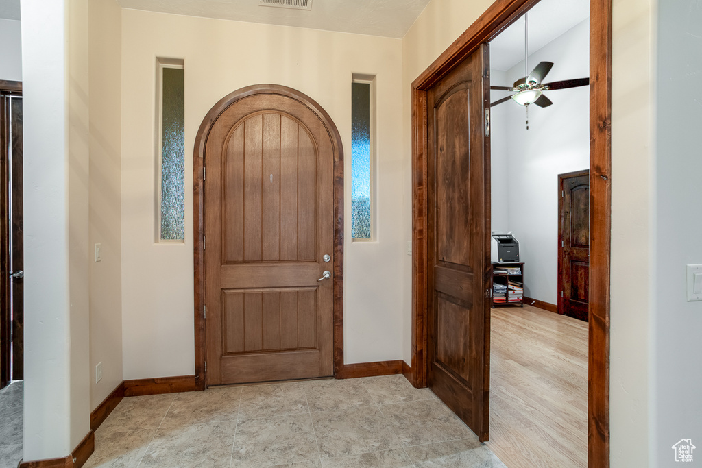 Foyer entrance with baseboards, a ceiling fan, and arched walkways