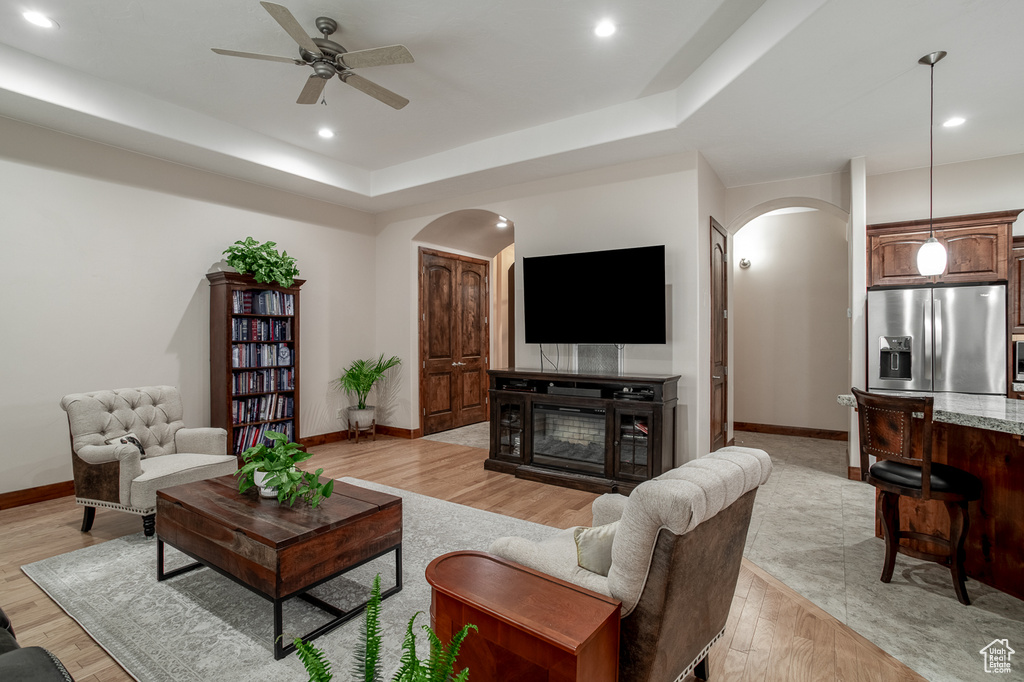 Living area with arched walkways, baseboards, light wood-style floors, and recessed lighting