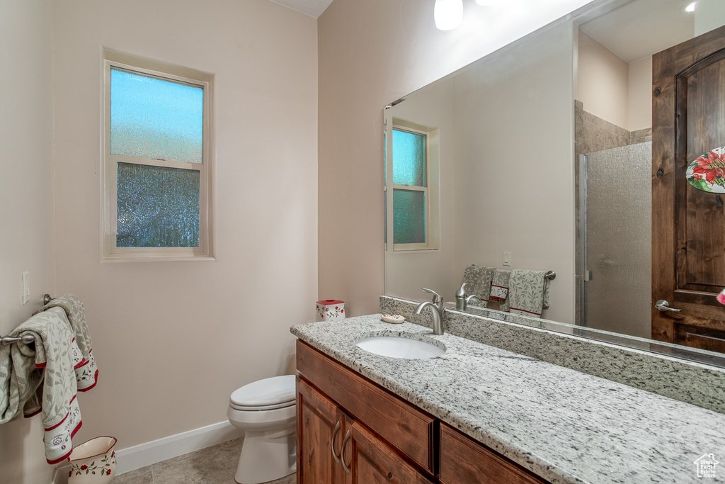 Full bathroom featuring vanity, toilet, a stall shower, baseboards, and tile patterned flooring