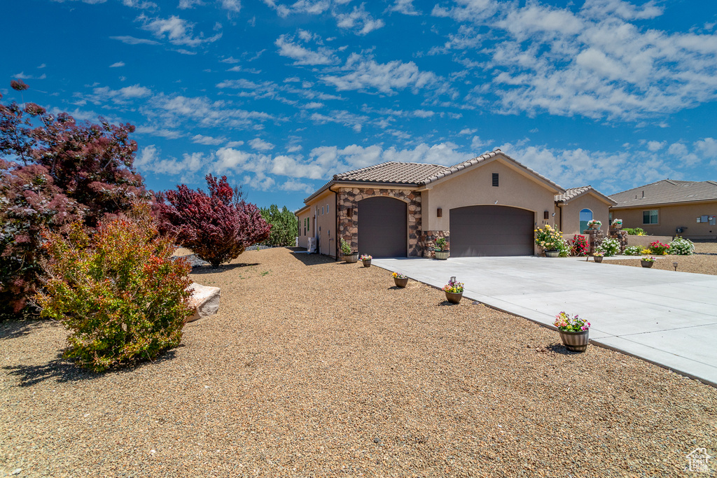 Mediterranean / spanish house featuring an attached garage, stone siding, concrete driveway, a tile roof, and stucco siding
