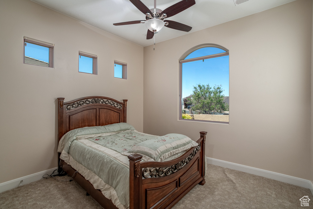 Bedroom with light carpet, baseboards, and a ceiling fan